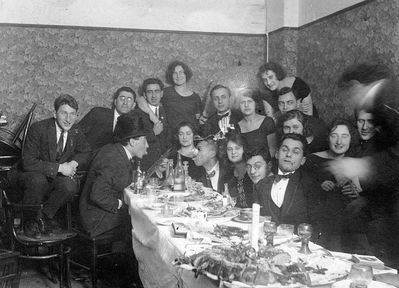 Company
Left to right.
At the table: ?, Anna Levin (Rogovski), Nosson Gens, Raja Drabkin (Feinstein), ?, Mischa Bakscht
Standing: Leo Markovitsch, ?, Dobruschkes?, ?, Samuil Levin,  Anna Feinstein, ?, ?,  ?, Margarete (Grete) Elian
